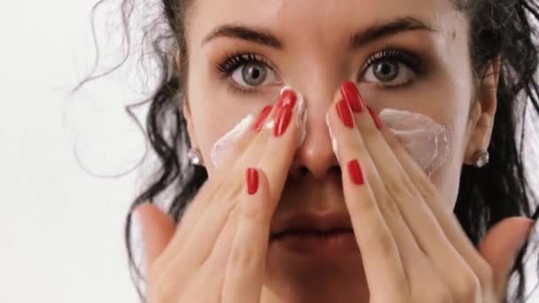 Женщина намазывает крем для лица на кожу — стоковое видео
