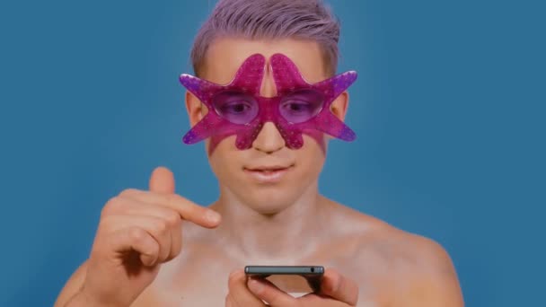 El hombre usa un teléfono sobre un fondo azul — Vídeos de Stock