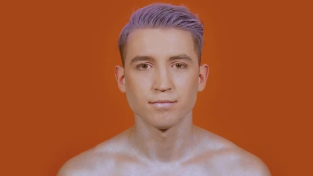 Hombre con un maquillaje brillante sobre un fondo naranja — Vídeo de stock