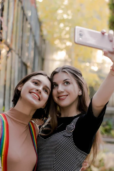Zwei schöne Mädchen beim Selfie mit dem Handy im Herbstpark — Stockfoto
