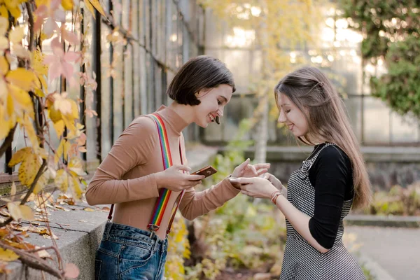 Zwei junge hübsche Studentinnen beim Telefonieren im Herbstpark — Stockfoto