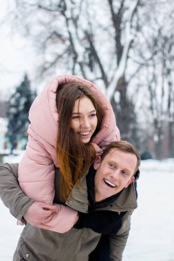 Mutlu genç bir çift kış yolcusu. Bir kadın kış karlı ormanda bir adam sürmek
