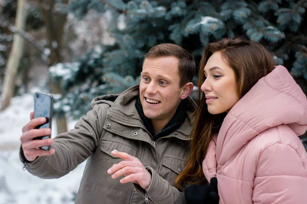 Glückliches Paar beim Fotografieren auf dem Smartphone über winterlichem Hintergrund — Stockfoto