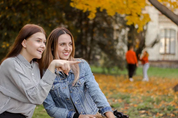 Nette Freundinnen bemerkten etwas abseits auf einer Bank im Herbstpark sitzend — Stockfoto