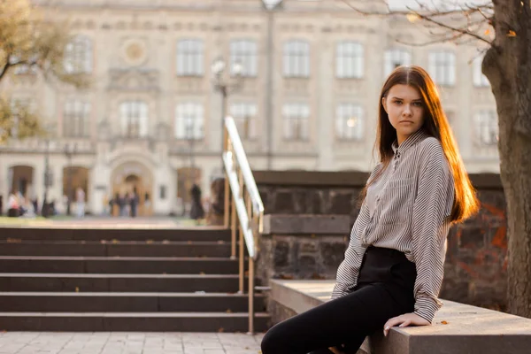 Bir öğrenci üniversiteye giden basamakların yanında oturur. — Stok fotoğraf