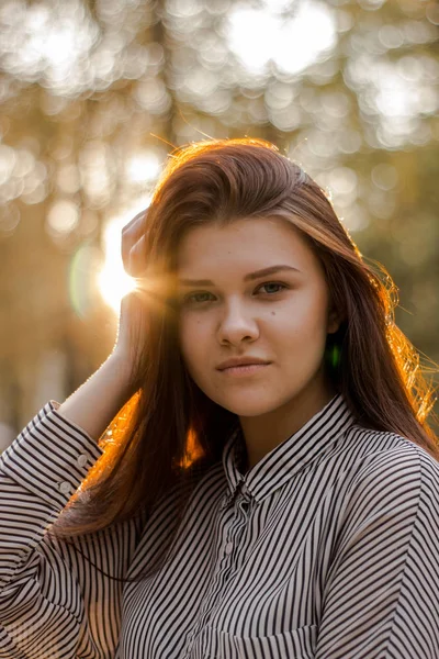 Porträtt av en vacker brun-haired flicka vars solnedgång solljus skimrar i håret — Stockfoto