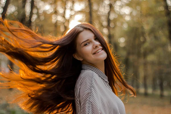 Portrét usměvavé hnědé dívky, jejíž sluneční svit ve vlasech jí kmitá slunce — Stock fotografie