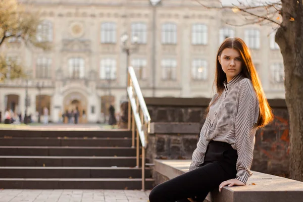 Student sedí nedaleko schodů vedoucích na univerzitu Stock Snímky