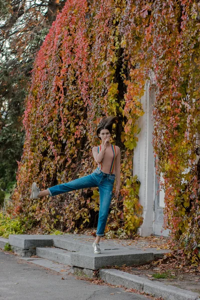 Fiatal lány mozgásban többszínű nadrágtartóban az őszi parkban — Stock Fotó