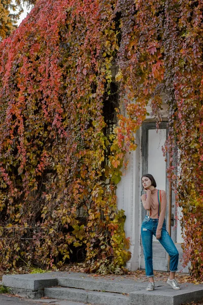 Junges Mädchen in bunten Hosenträgern im Herbstpark — Stockfoto