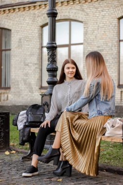 Sonbahar parkında bir bankta konuşan kızlar