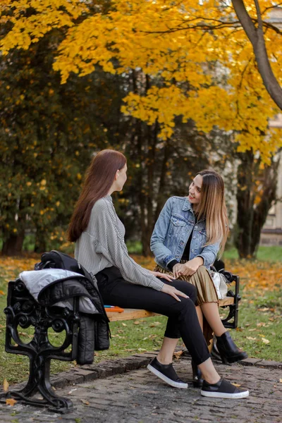 Freundinnen unterhalten sich auf einer Bank im Herbstpark — Stockfoto