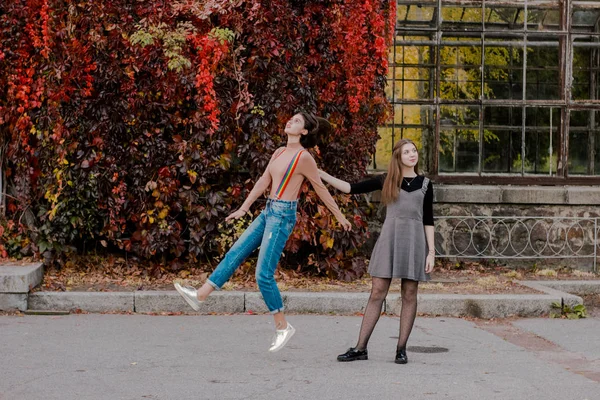 Het meisje neemt af naast de jonge vrouw die haar wandelend in het herfst Park houdt — Stockfoto