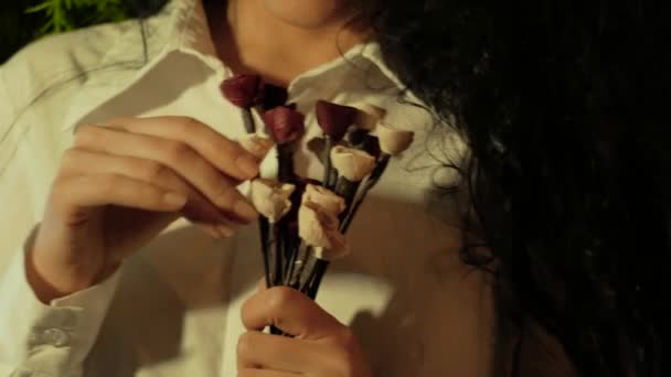 A beautiful woman holds out her hand with a bouquet and bring it to her face — Stock Video