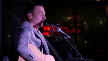 Adam gitar çalıyor ve şarkı söylüyor