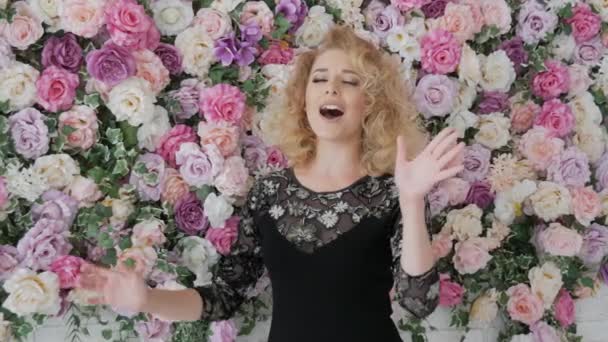 Sångaren sjunger på bakgrunden av blommor — Stockvideo
