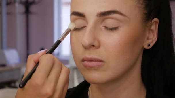 Hand applies a brush to the upper eyelid — Stock Video
