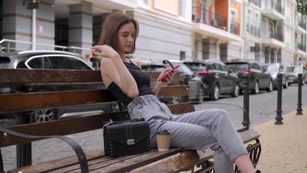 Cute girl używać czerwony smartfon odkryty — Wideo stockowe