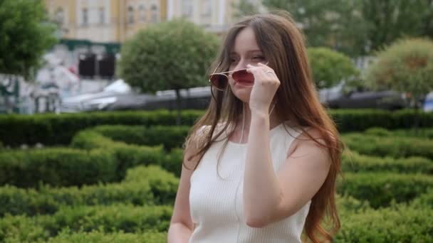 Молодая женщина надевает солнечные очки — стоковое видео