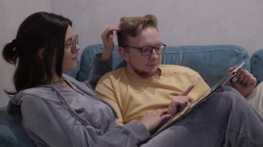 Gözlüklü genç bir çift, bir albüm boyunca yan yana oturup rahatlığın tadını çıkarıyorlar. Yüz ifadeleri samimi bir endişe veriyor, bağlantılarını vurguluyor.