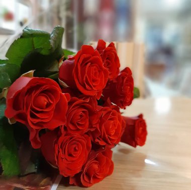 Bir buket kırmızı gül kapalı bir masada yatıyor.