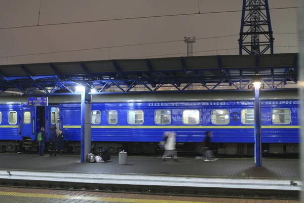 夜间列车在车站的铁轨上 乘客在月台上移动 — 图库照片