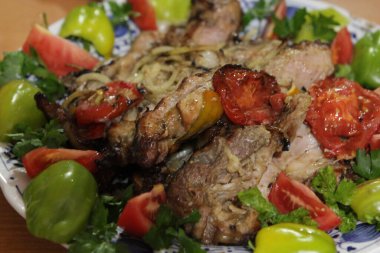 Sebze ve otlarla dolu tabakta ızgara hazır domuz eti.