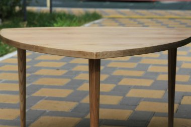 Geometrik kompozisyonda sokak tuğlaları üzerinde doğal ahşap masa ve bacakların yan görüntüsü