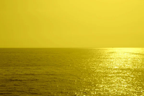 太陽が地平線に下って来る 海に夏シンプルな背景 黄色単色きらびやかな夕日 — ストック写真