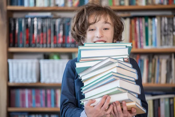 Школьник читает книги, милый мальчик читает книги в библиотеке — стоковое фото