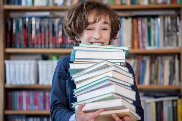 Школьник читает книги, милый мальчик читает книги в библиотеке — стоковое фото