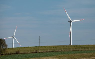 Yeşil tepelerde rüzgar türbinleri, yeşil alanda elektrik üretimi için yel değirmenleri grubu.
