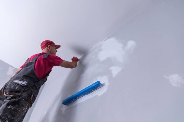 Ev ressamı, boyacı, ahşap merdiveni ve boş duvarı var.