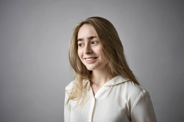 Joy, happiness and positive feelings concept. Portrait of fair haired friendly young female in stylish white shirt smiling happily, rejoicing at good news, present, exams or success at work