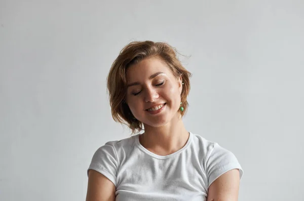 Cheerful young woman with short messy hair looking sideways with sly cunning smile.