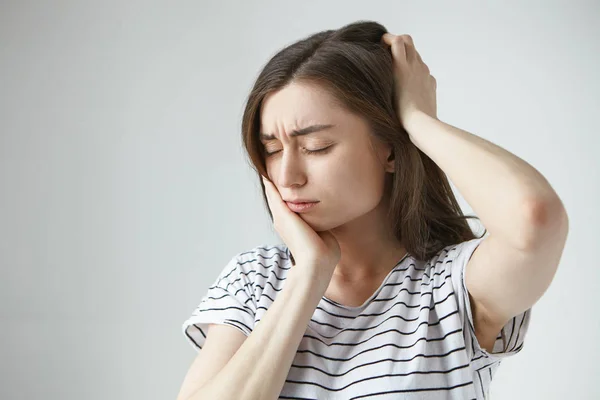 Stressed young woman suffering having bad toothache and headache.