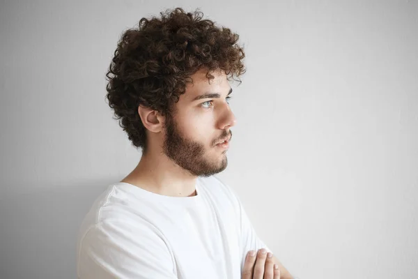 Man with curly hair, thick beard posing isolated in studio with blank copy space wall