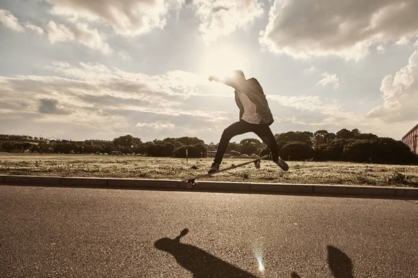 Youth, leisure, recreation, hobby, active lifestyle and extreme sports. Outdoor portrait of silhouette of teenager jumping high with skate in air going to land on board while doing kick flip