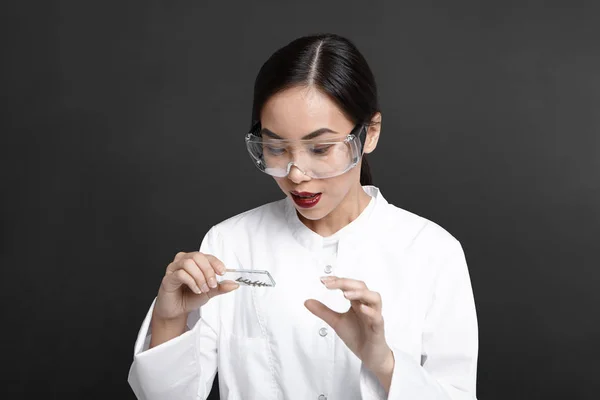 Horizontal shot of young Asian woman scientist analyzing cell culture samples, holding glass plate, collecting plant DNA in laboratory. Science, research, biochemistry and microbiology concept