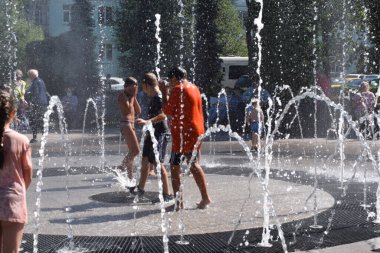 Çocuklar çeşmede suyla oynuyorlar.