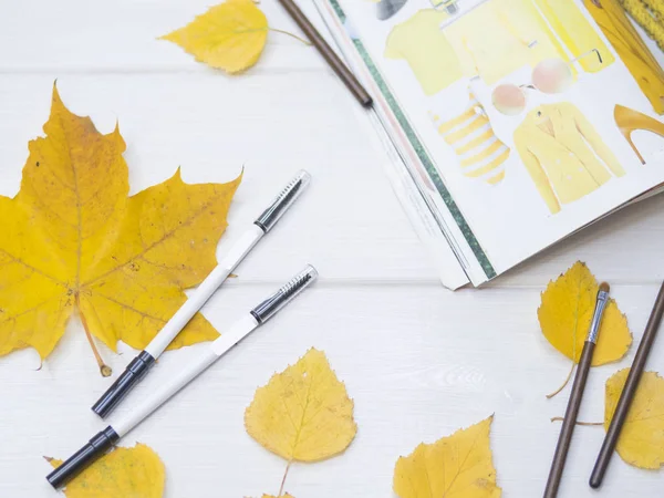eyebrow pencil. Autumn leave. Fashion magazine. Tweezers. Yellow background. On a white tree.