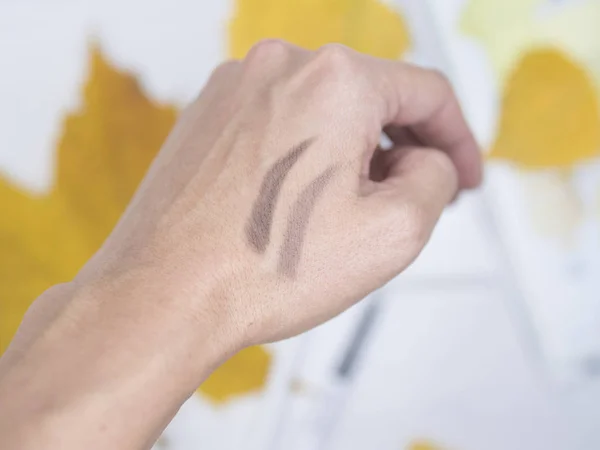 On the hand painted eyebrows. Soft background. Yellow background. On a white tree.