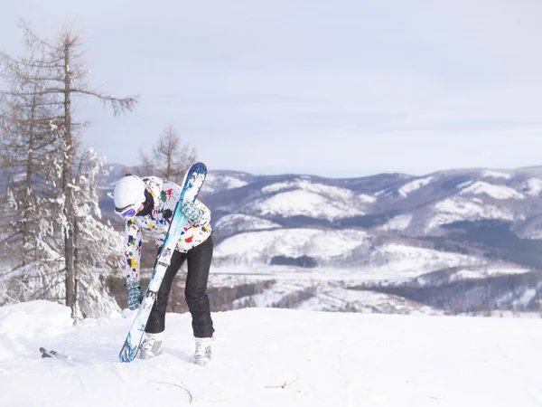 girl holding skis in her hands Happy girl holding skis and ski poles in hands, sitting in snow