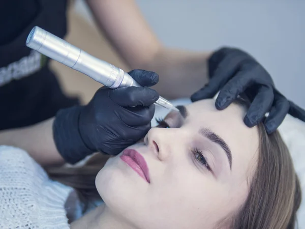Permanent make up on eyebrows. Master at work with the eyebrows makes microbleeding tattoo