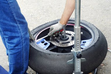 bir adam bir motosiklet tekerlek lastikleri değiştirmek iş elbiseleri