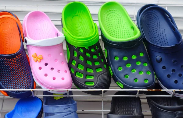 multi-colored rubber slippers in a showcase with round holes, a theme of shoes and clothes for everyday life