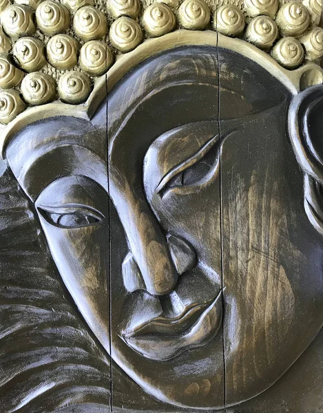 Buddha face, wood carving. Handmade bas-relief wooden