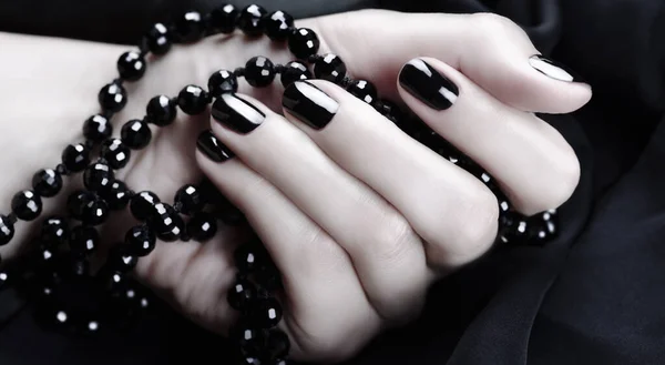 Female hand with black manicure on a black background