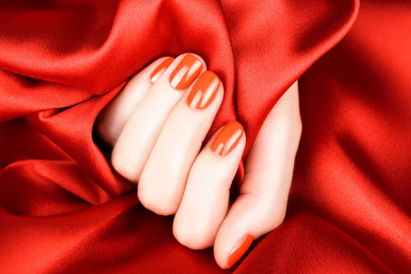 Kırmızı Ipek Arka Planda Parlak Kırmızı Manikürlü Kadın Parmaklar — Stok fotoğraf