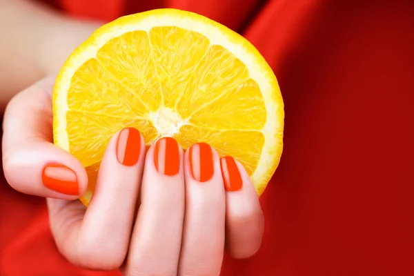 Mão Feminina Com Manicure Cor Vermelha Brilhante Segurando Fatia Laranja — Fotografia de Stock